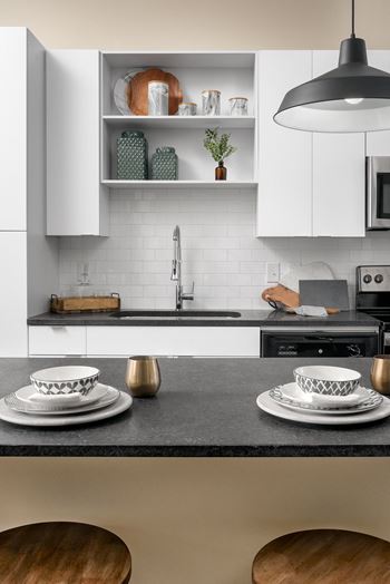 a kitchen with white cabinets and a black countertop at Livano Springdale, Louisville Kentucky